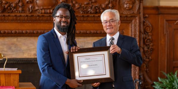 Douglas Flowe stands next to Dean Feng Sheng Hu, they both hold a framed award: Dean's Award for Diversity Advancement