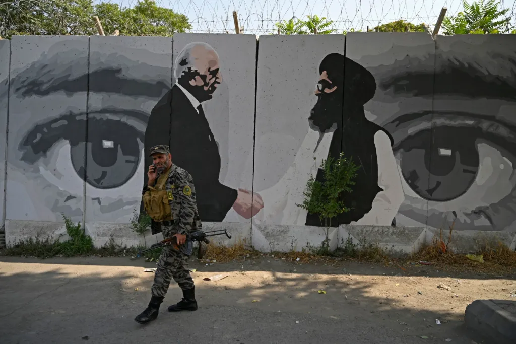 "A security personnel walks past a wall mural with images of US Special Representative for Afghanistan Reconciliation Zalmay Khalilzad (L) and Taliban co-founder Mullah Abdul Ghani Baradar, in Kabul on July 31, 2020 / Wakil Kohsar / AFP via Getty Images"