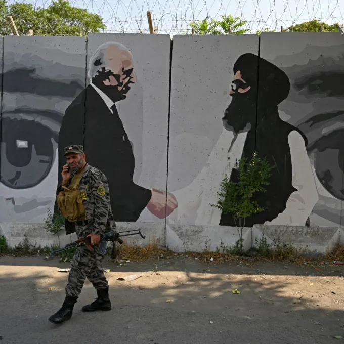 "A security personnel walks past a wall mural with images of US Special Representative for Afghanistan Reconciliation Zalmay Khalilzad (L) and Taliban co-founder Mullah Abdul Ghani Baradar, in Kabul on July 31, 2020 / Wakil Kohsar / AFP via Getty Images"