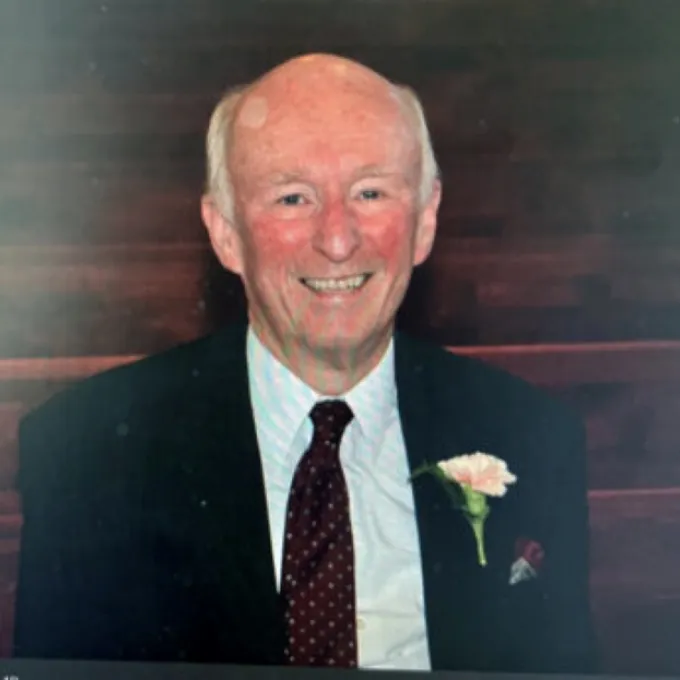 Image of Richard Walters provided by family. He is wearing a black suit jacket with a white buttoned shirt, a rose in his lapel pocket. He has grey hair and is smiling.